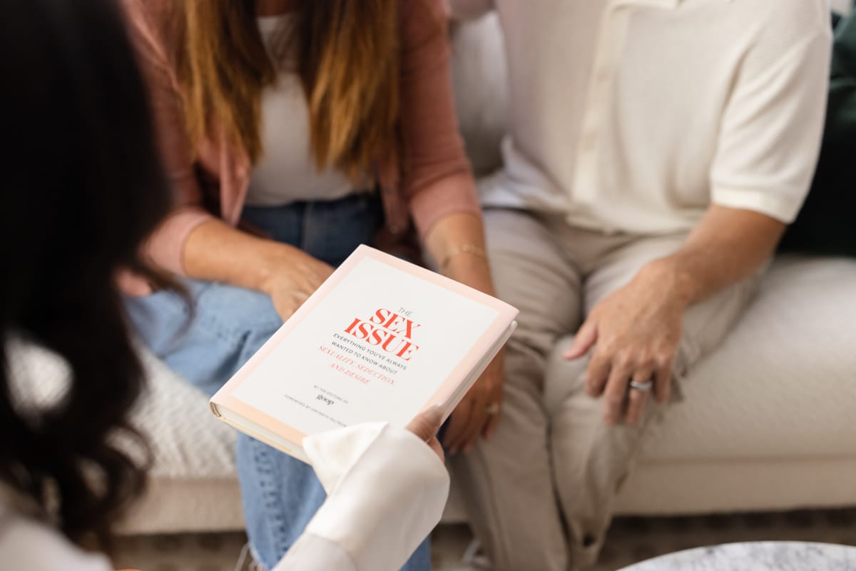 Hand holding a book titled 'Sex Health Issue' on sexual well-being resources.