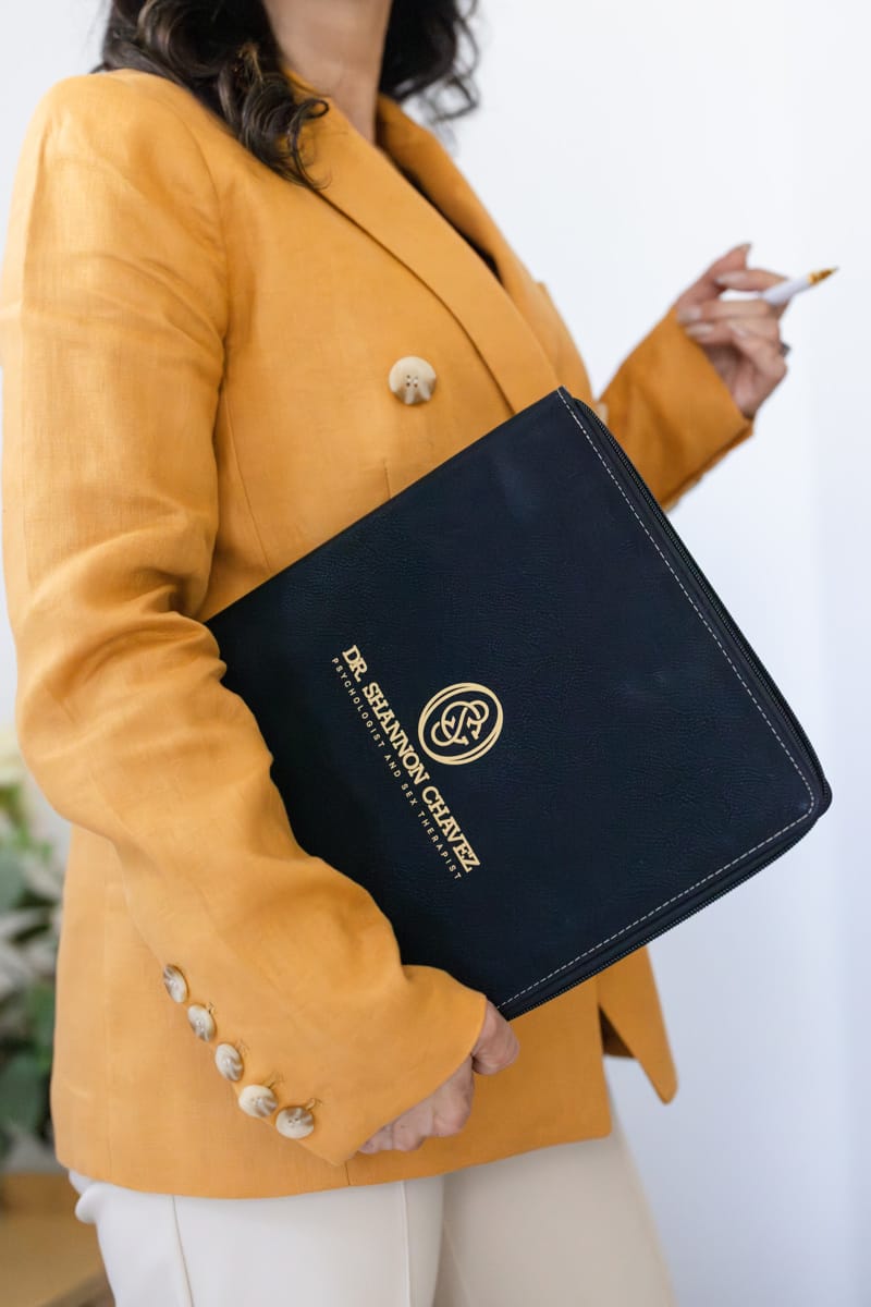 Dr Chavez in Burnt Orange Suit Holding File