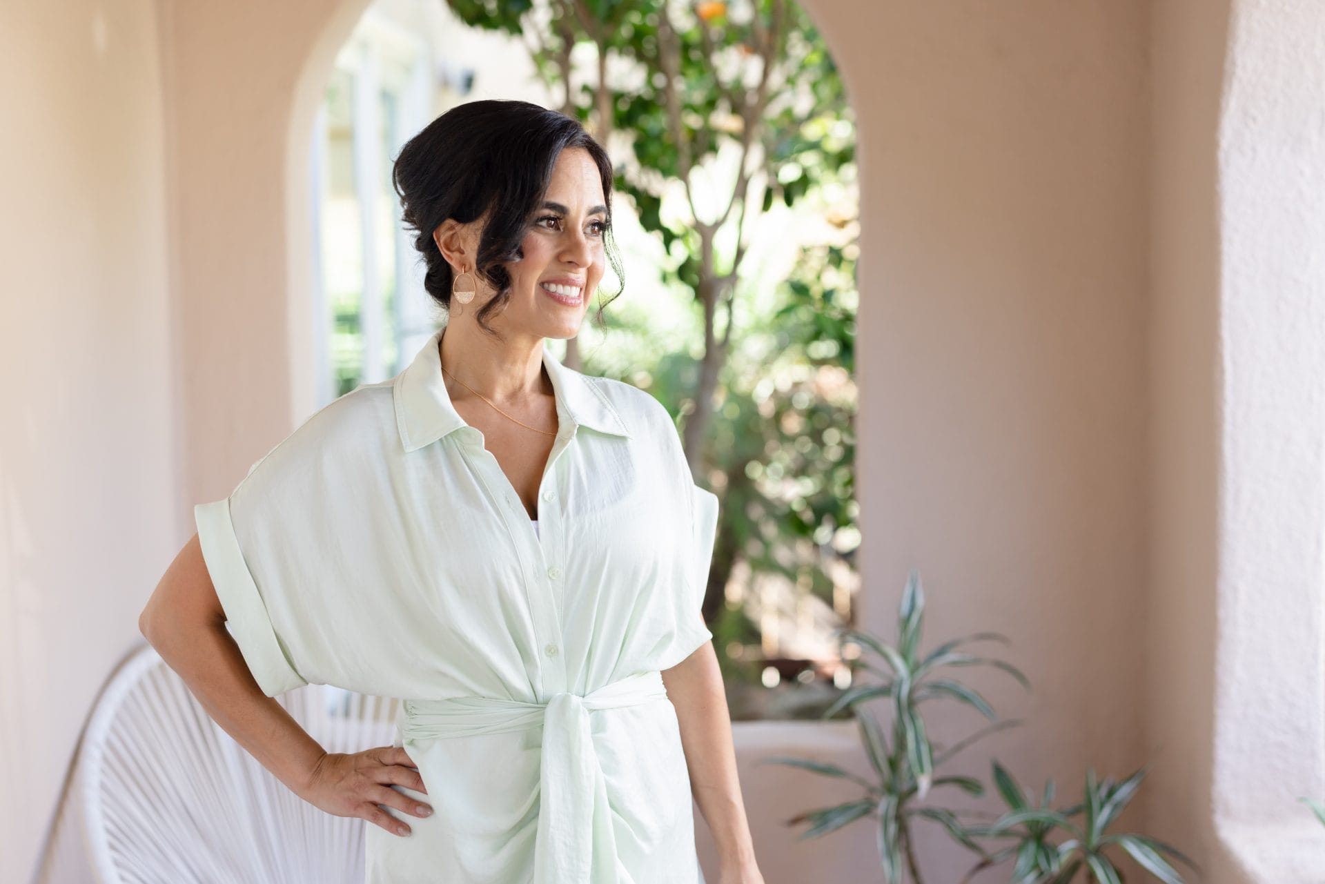 Dr. Shannon Chavez's outdoors on a balcony, dressed in white attire.