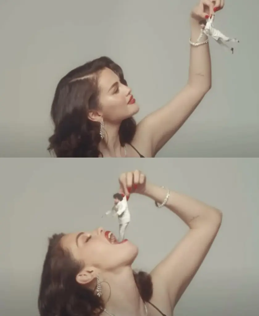 Selena Gomez playfully holds a miniature Benny Blanco in her hand in a surreal scene from the “Sunset Boulevard” music video, symbolizing themes of erotic power and consumption.