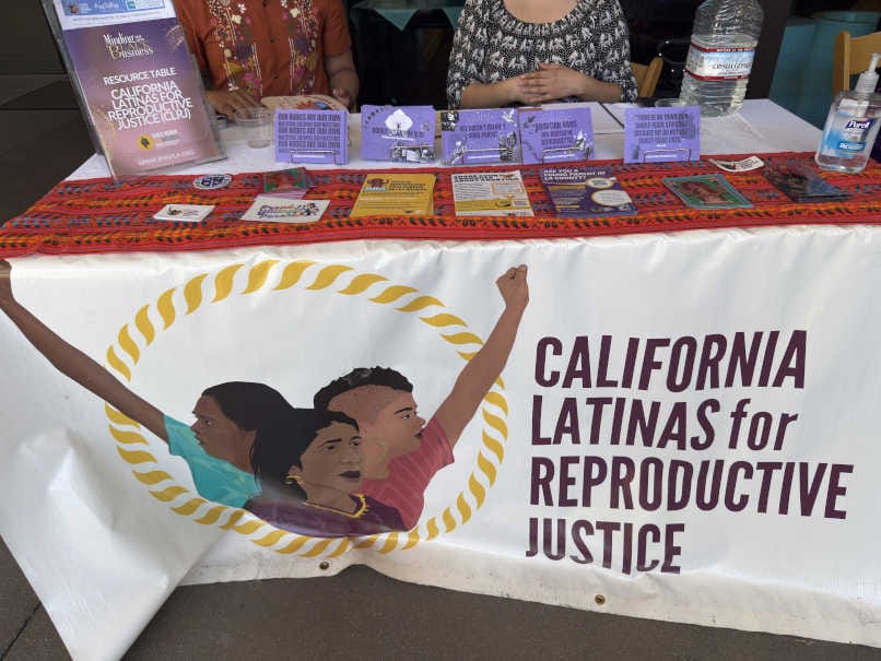California Latinas for Reproductive Justice resource table at the Black Women for Wellness Annual Reproductive Justice Conference, displaying educational materials on bodily autonomy, reproductive health, and family well-being.