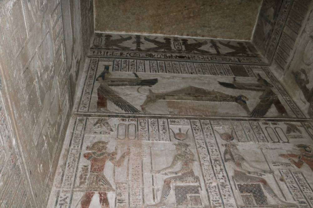 Tomb relief showing Osiris on the funerary bier with Isis and Nephthys, symbolizing resurrection and eternal life.