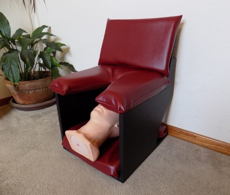 A burgundy and black queening chair designed for supported facesitting and comfortable intimate play.