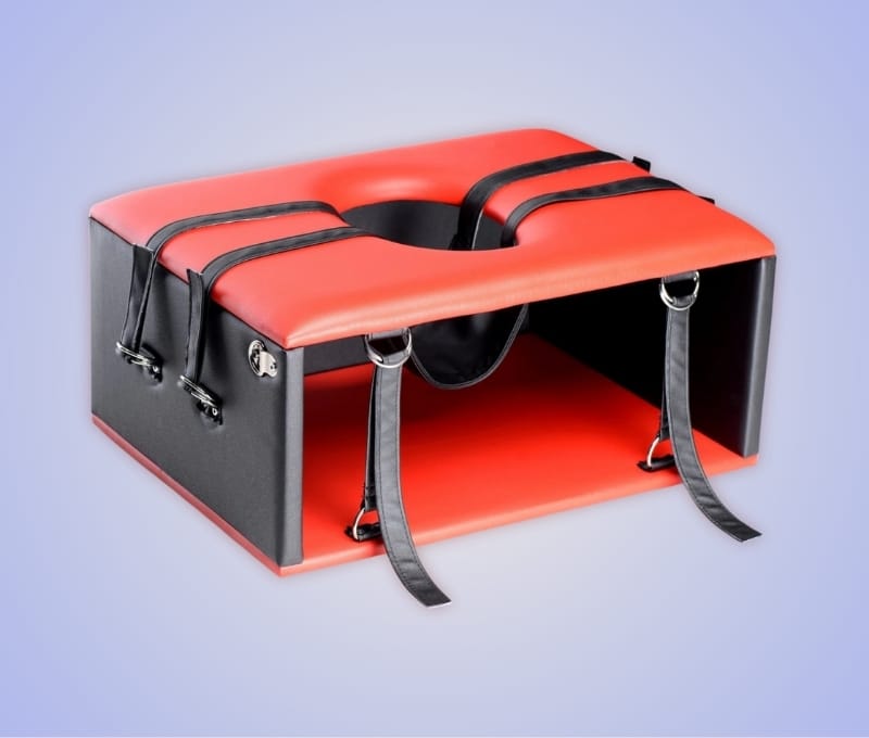A red and black queening or kinging chair designed for intimacy and comfortable oral positioning.