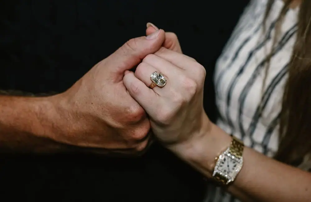 Close-up of Taylor Swift and Travis Kelce holding hands, showing her engagement ring.